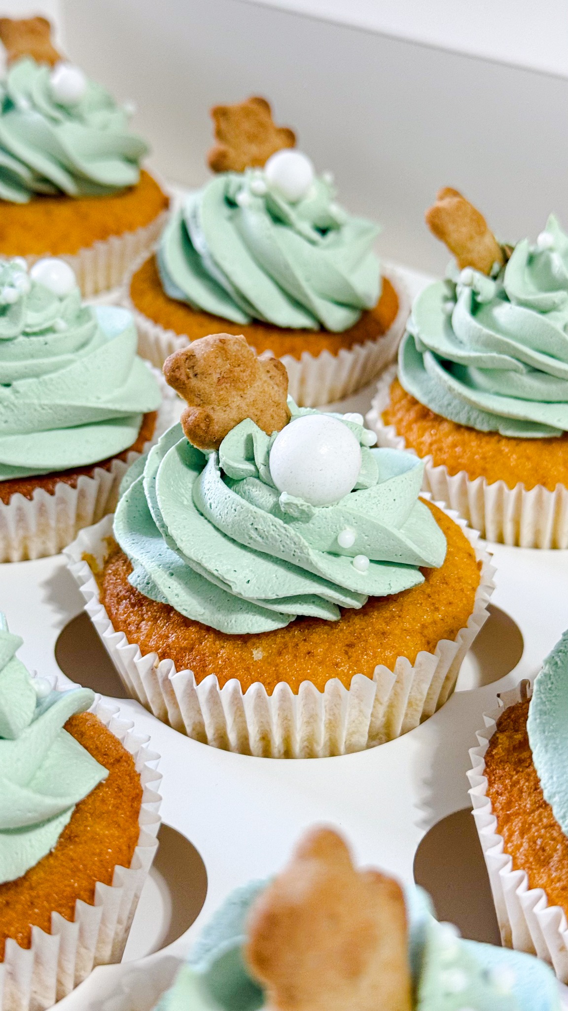 Cupcakes decorados com creme verde-claro e pequenos topos